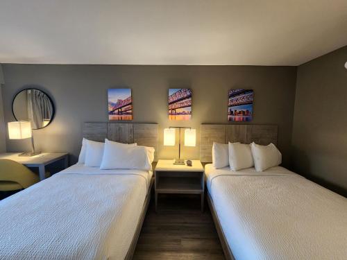 two beds in a room with two tables and two lamps at Days Inn by Wyndham Kenner/New Orleans Airport South in Kenner