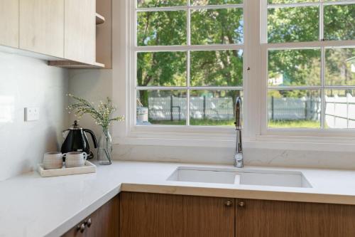 une cuisine avec un évier et une fenêtre dans l'établissement Lavender Cottage Alpine Southern Highlands, à Alpine