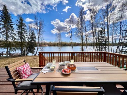 a wooden table on a deck with a view of a lake at Serene Four Bedroom Lakefront Home in Wasilla
