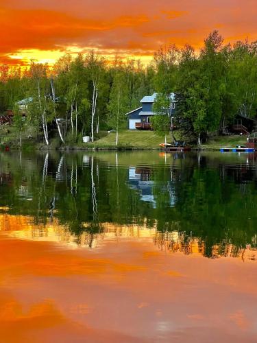a house on the shore of a lake at sunset at Serene Four Bedroom Lakefront Home in Wasilla