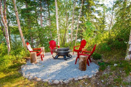 a group of chairs around a fire pit in the woods at Serene Four Bedroom Lakefront Home in Wasilla