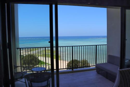 a room with a balcony with a view of the ocean at Ryukyu Hotel & Resort Nashiro Beach in Itoman