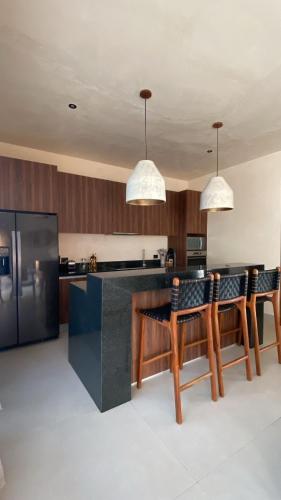 a kitchen with a counter with chairs and a refrigerator at Bali 4BR Villa w Pool, Rooftop Jacuzzi and BBQ in Tulum