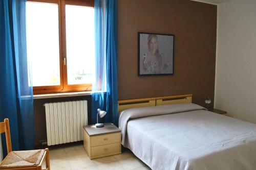 a bedroom with a bed and two windows with blue curtains at Residenza Benini in Bardolino