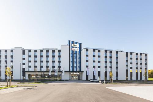 a large white building with a parking lot in front at Candlewood Suites Augsburg in Augsburg