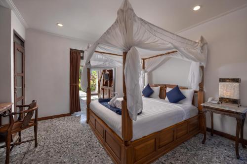 ein Schlafzimmer mit Himmelbett und Tisch in der Unterkunft Taman Harum Cottages in Ubud