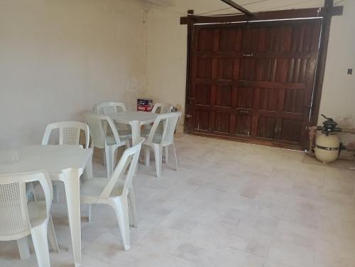 a room with white tables and white chairs and a door at Espaço Gardenias II in Guaratinguetá