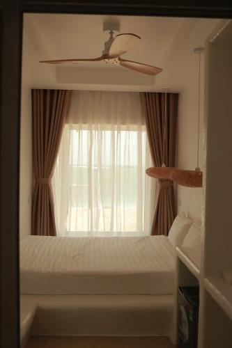 a bedroom with a bed with a ceiling fan and a window at Chiu Chiu Resort Đảo Phú Quý in Cu Lao Thu
