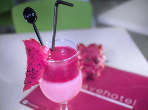 a pink drink with a strawberry on a table at favehotel Rungkut Surabaya in Surabaya