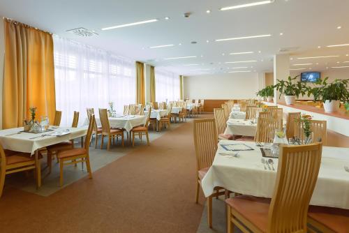 uma sala de jantar com mesas e cadeiras brancas em Hotel Lineas em Presov