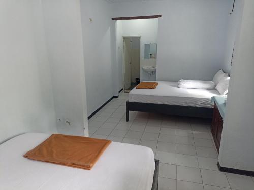 a small room with two beds and a bathroom at Bonsai Guesthouse Banyuwangi in Banyuwangi