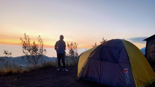 a man is standing next to a tent at LuxeTent Batur Peak in Kintamani