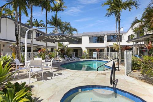a pool with chairs and an umbrella next to a building at Noosa Place Resort in Noosaville