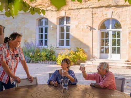 un groupe de personnes assises autour d'une table en bois dans l'établissement Maison troglodyte élégante avec spa, salle de jeux et jardin clos à Vouvray - FR-1-381-87, à Vouvray