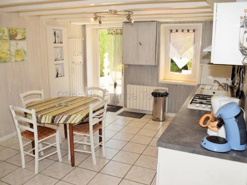 une cuisine avec une table et des chaises dans une cuisine dans l'établissement Gîte rural 1 chambre, cour close, équipements bébé, Wi-Fi, proche mini-golf, non fumeur, tout inclus - FR-1-381-24, à La Tour-Saint-Gelin