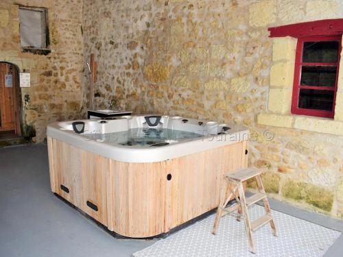 a wooden bath tub in a room with a stool at Élégante Demeure 17e avec Spa, Sauna et Authentique Cheminée, proche Châteaux de la Loire - FR-1-381-348 in Les Essards
