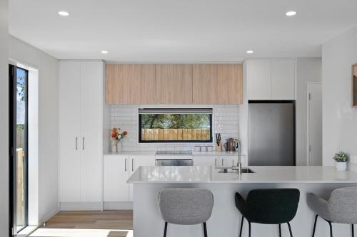 a kitchen with a white counter and some chairs at Lux Local Living in Christchurch