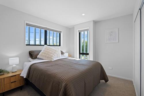 a bedroom with a bed and two windows at Lux Local Living in Christchurch
