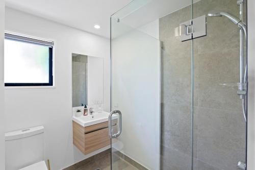 a bathroom with a glass shower and a sink at Lux Local Living in Christchurch