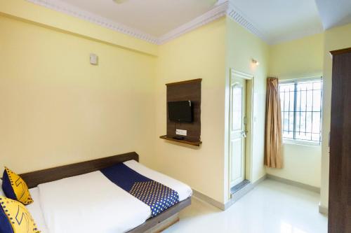 a bedroom with a bed and a tv on the wall at Hotel O SK Lodge in Kumbalgod