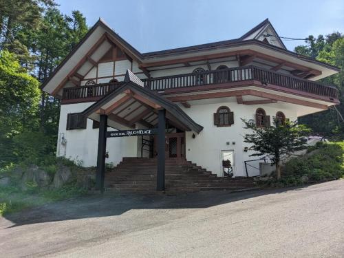 una grande casa bianca con balcone in cima di ホテル竜王ヴィレッヂ a Yamanouchi