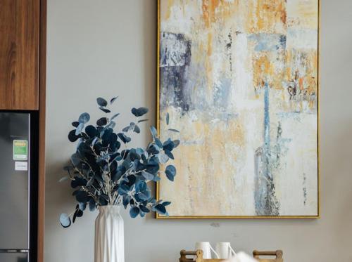 a vase with flowers in it next to a painting at Hi-Home Suites - Penstudio Westlake Hanoi in Hanoi