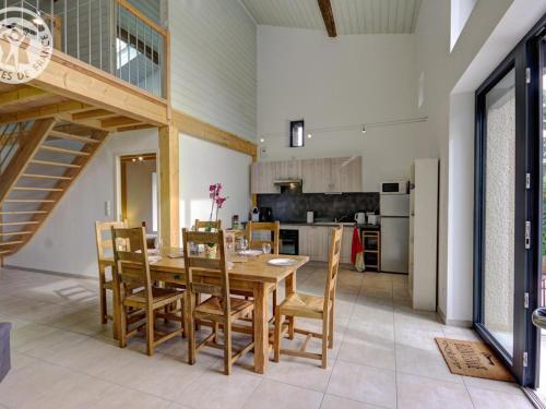 une cuisine et une salle à manger avec une table et des chaises en bois dans l'établissement Maison spacieuse avec terrasse, jardin et poêle à bois à Saint-Héand - FR-1-496-146, à Saint-Héand