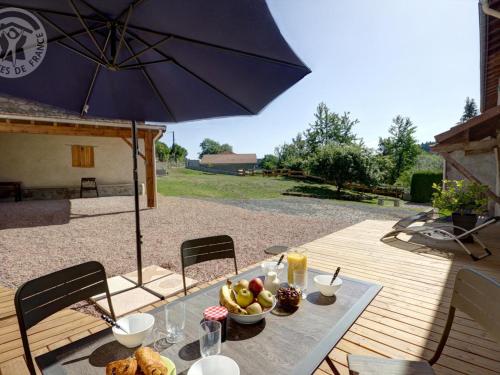 - une table avec un bol de fruits et un parasol dans l'établissement Gîte confortable avec jardin clos et wifi - FR-1-496-171, à Champoly