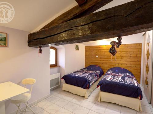 - 2 lits dans une chambre avec un mur en bois dans l'établissement Gîte confortable avec jardin clos et wifi - FR-1-496-171, à Champoly