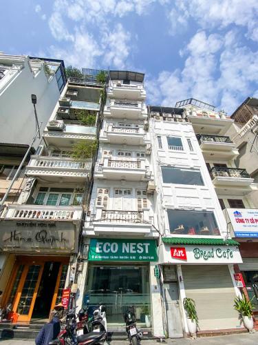 a tall white building with a sign in front of it at Eco Nest Hotel Đình Ngang in Hanoi