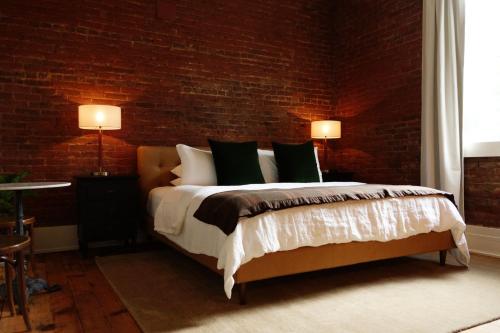 a bedroom with a bed and a brick wall at Imperial Hotel + Restaurant in Amador City