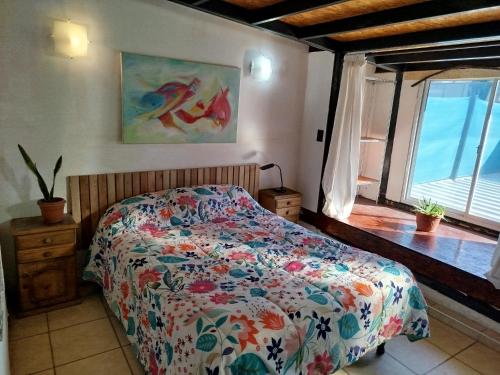 - une chambre avec un lit avec une couette à fleurs et une fenêtre dans l'établissement Mi alma deptos, à Mendoza