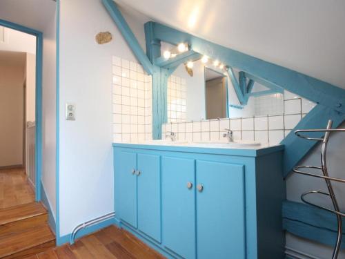 Un baño azul con lavabo y espejo. en Grange restaurée avec jardin, charme et confort près d'Alençon - FR-1-497-24, en Alençon