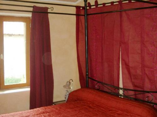 a bedroom with a bed with a red curtain at Gîte calme avec terrasse et animaux acceptés - FR-1-496-47 in Sainte-Foy-Saint-Sulpice