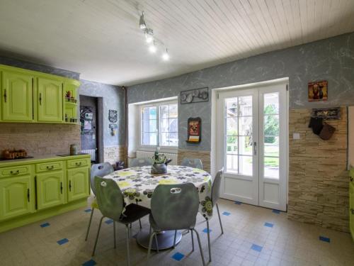 une cuisine avec des armoires vertes, une table et des chaises dans l'établissement Maison en pierre avec grand jardin, proche Vézère, idéale pour familles et amateurs de pêche - FR-1-616-219, à Limeuil