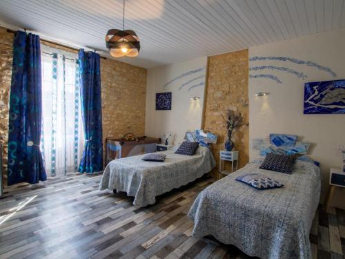 Maison en pierre avec grand jardin, proche Vézère, idéale pour familles et amateurs de pêche - FR-1-616-219 في Limeuil: سريرين في غرفة مع ستائر زرقاء