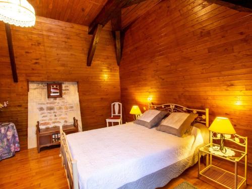 une chambre avec un lit et un mur en bois dans l'établissement Maison en pierre avec grand jardin, terrasse, cheminée, proche des sites préhistoriques des Eyzies - FR-1-616-174, à La Mouthe
