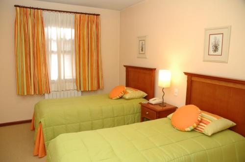 a hotel room with two beds and a window at Pousada Chablis in Campos do Jordão