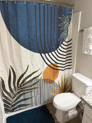 a bathroom with a shower curtain and a toilet at Apartment in Medical Center near NRG Free Parking in Houston