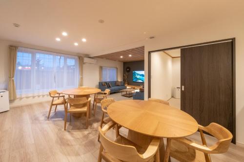 a living room with two wooden tables and chairs at 旭神ゲストハウス in Asahikawa