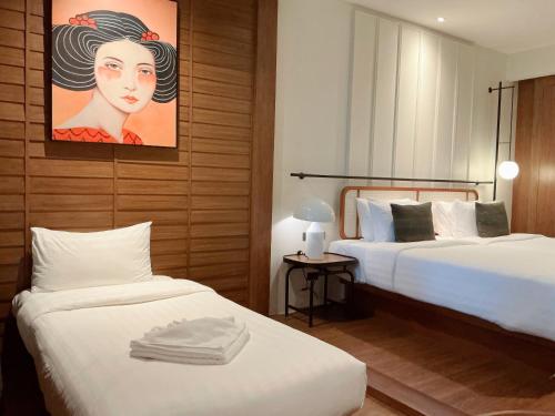 a hotel room with two beds and a painting on the wall at Hotel Loy Chiang Mai in Chiang Mai