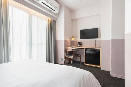a hotel room with a bed and a desk with a television at Hotel Asakusa KANNONURA in Tokyo