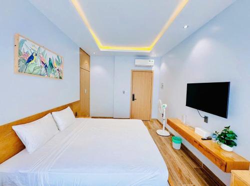 a bedroom with a large white bed and a flat screen tv at Bay Homestay in Cam Lâm