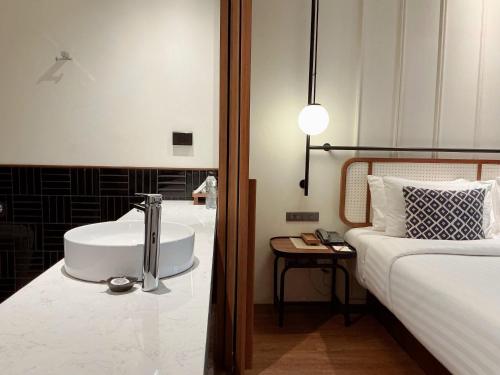 a bathroom with a sink next to a bed at Hotel Loy Chiang Mai in Chiang Mai