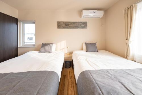 two twin beds in a room with a window at 旭神ゲストハウス in Asahikawa