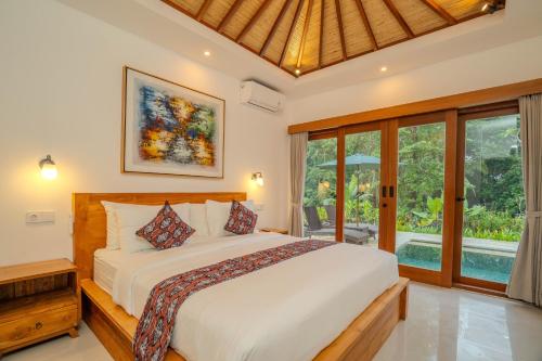 a bedroom with a bed and a large window at Arca Jungle View Luxury Villa Ubud in Ubud