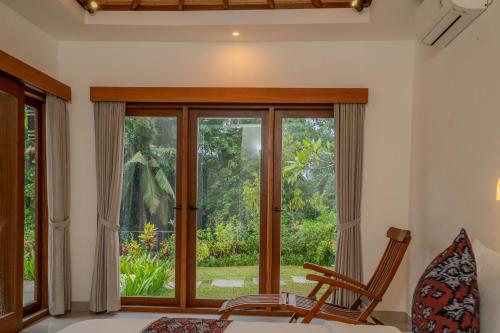 a room with a window and a bed and a chair at Arca Jungle View Luxury Villa Ubud in Ubud