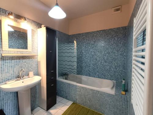 une salle de bain carrelée bleue avec un lavabo et une baignoire dans l'établissement Villa avec terrasse à 400m de la mer à Pleumeur-Bodou - FR-1-368-400, à Pleumeur-Bodou