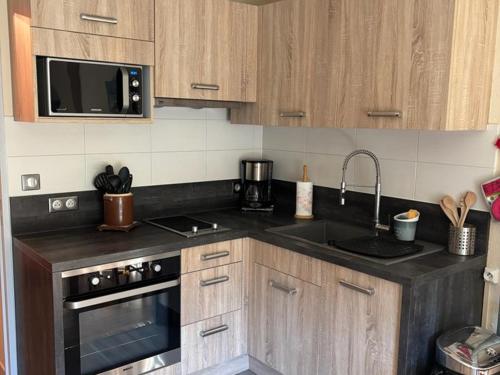 une cuisine avec un évier et un micro-ondes dans l'établissement Charmant T2 avec Balcon Proche Ski - FR-1-787-127, à Laveissière