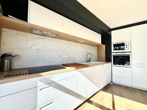 une cuisine avec des armoires blanches et un évier dans l'établissement Charmante maison familiale pour 10 personnes, spacieuse et confortable - FR-1-309-511, à Banyuls-sur-Mer